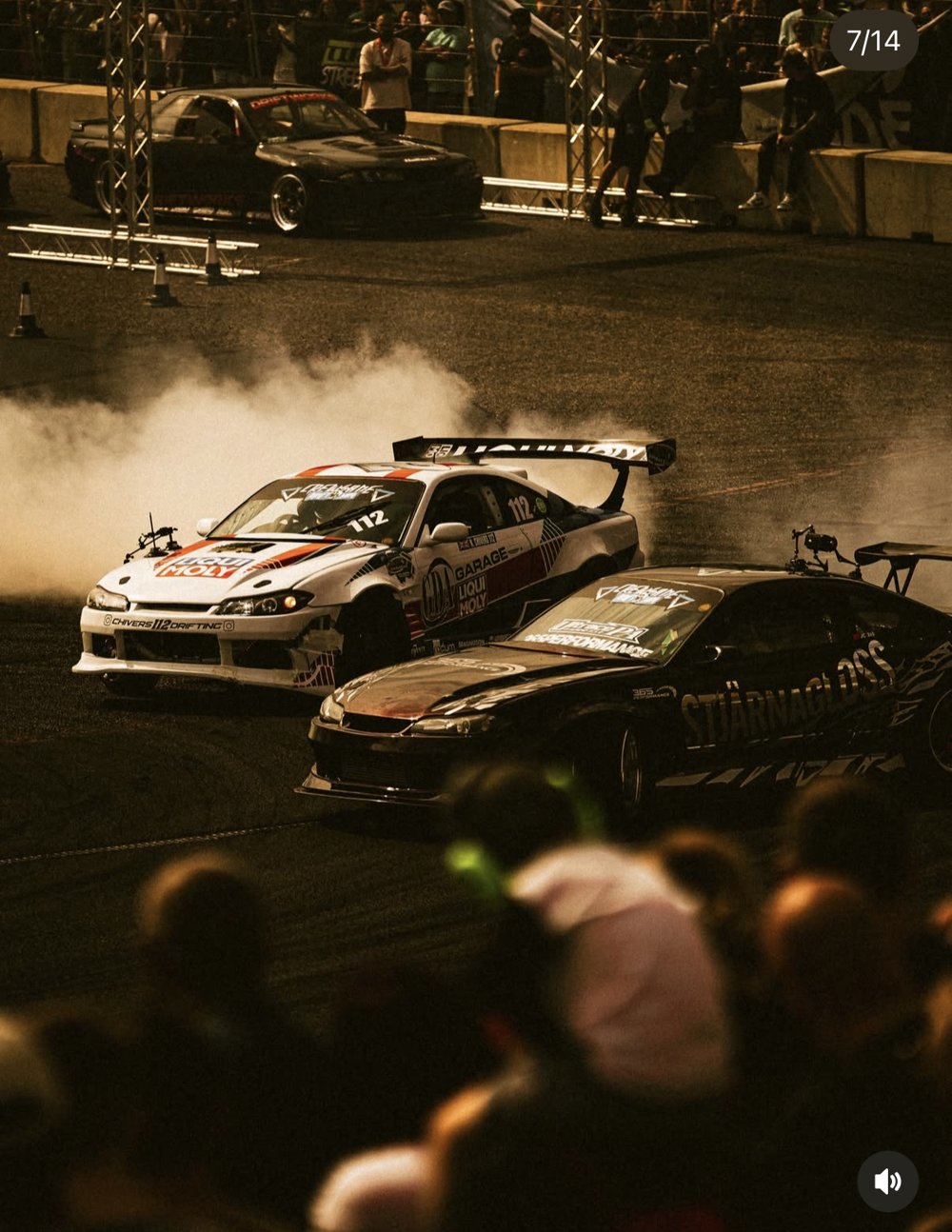 Drift racing de nuit - deux voitures cote a cote, fumee de pneus