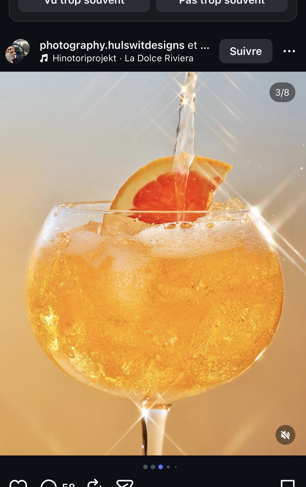 Gros plan du cocktail Sunset Citrus glacé, quartier d'agrume et éclats de lumière