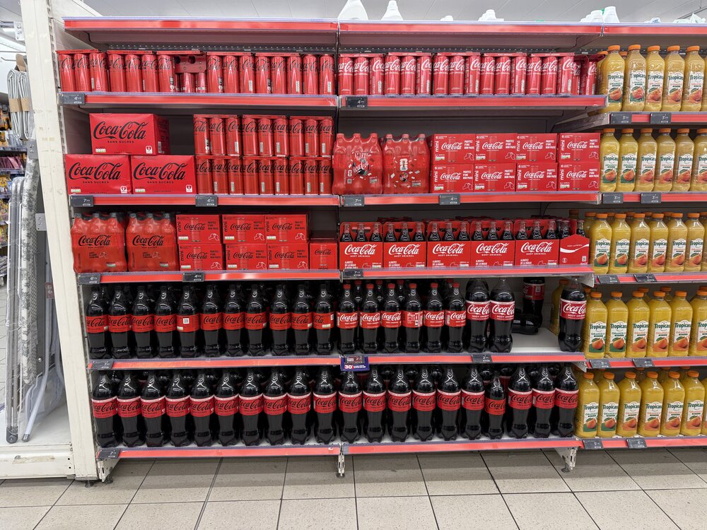 Rayon Coca-Cola — canettes et bouteilles verre, formats multiples empilés sur plusieurs étagères