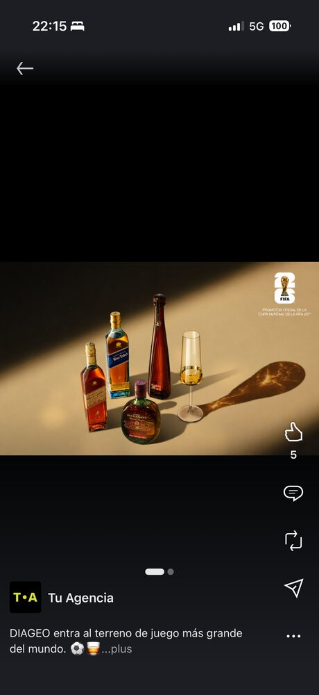 Still-life de bouteilles de spiritueux Diageo (whisky, liqueur) et verre à dégustation sur fond chaud, logo Coupe du Monde FIFA