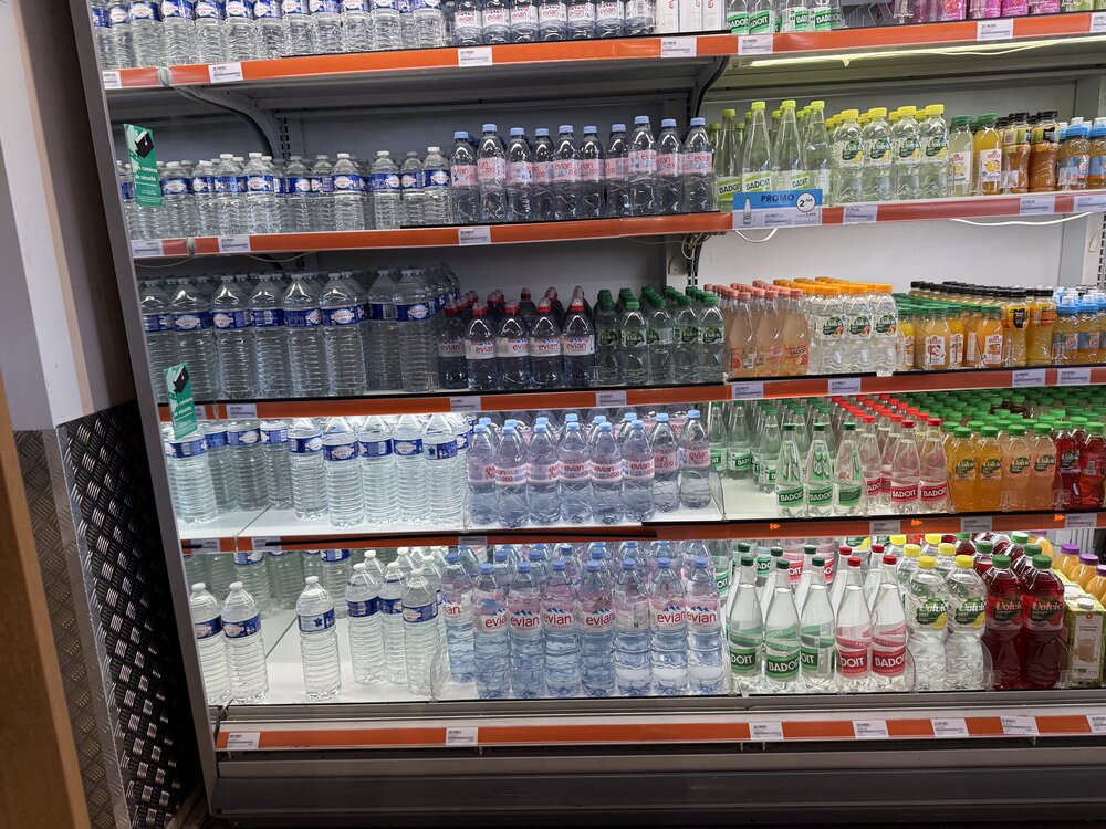 Linéaire eaux plates et gazeuses — Evian, Volvic, Badoit, Cristaline, codes couleur bouchon par gamme