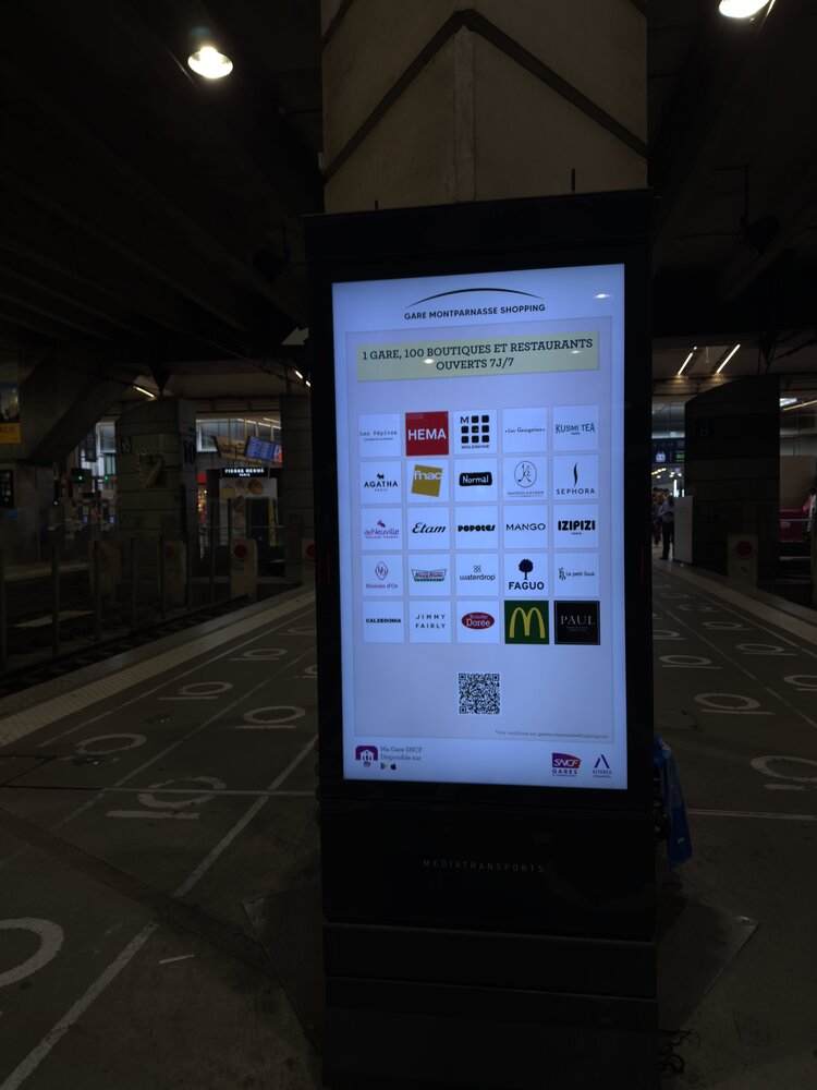 Totem digital « 1 gare, 100 boutiques et restaurants ouverts 7/7 » — grille de logos enseignes (Sephora, Paul, Monoprix, McDonald's, Hema...)