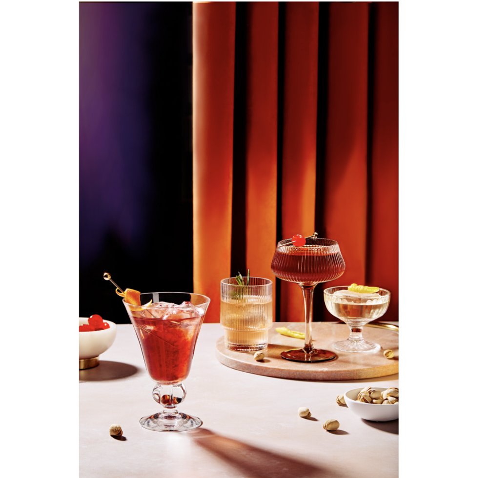 4 cocktails styles sur table claire, fond rideau degrade violet vers orange