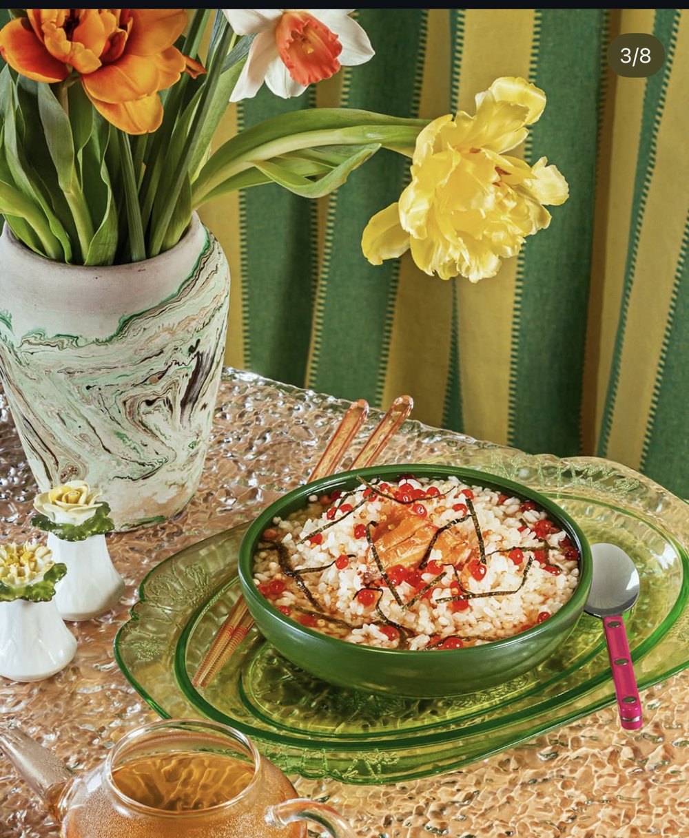 Bol de congee tenu à table, nappe rouge vif, plante verte en arrière-plan