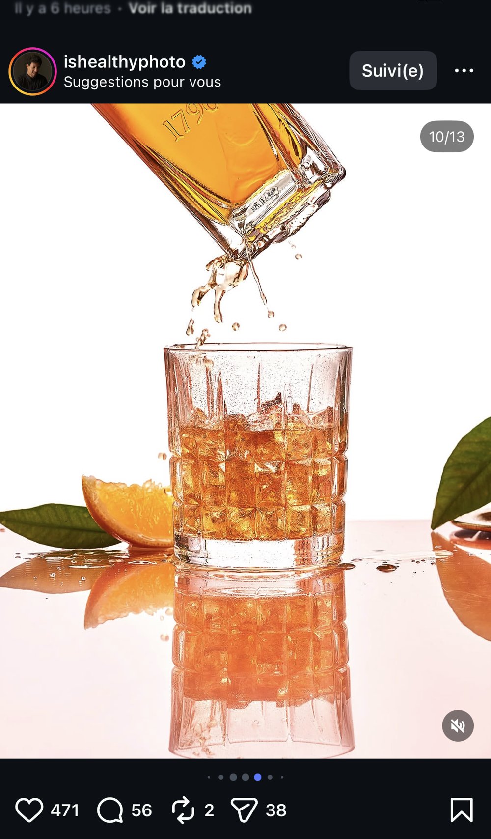 Verre de whisky avec éclaboussure figée et tranche d'orange, fond orangé lumineux