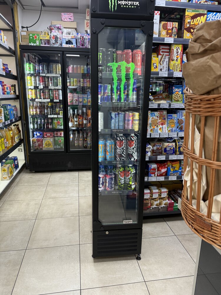 Frigo tour Monster Energy dédié — vue rapprochée du facing, rayon céréales/biscuits en arrière-plan