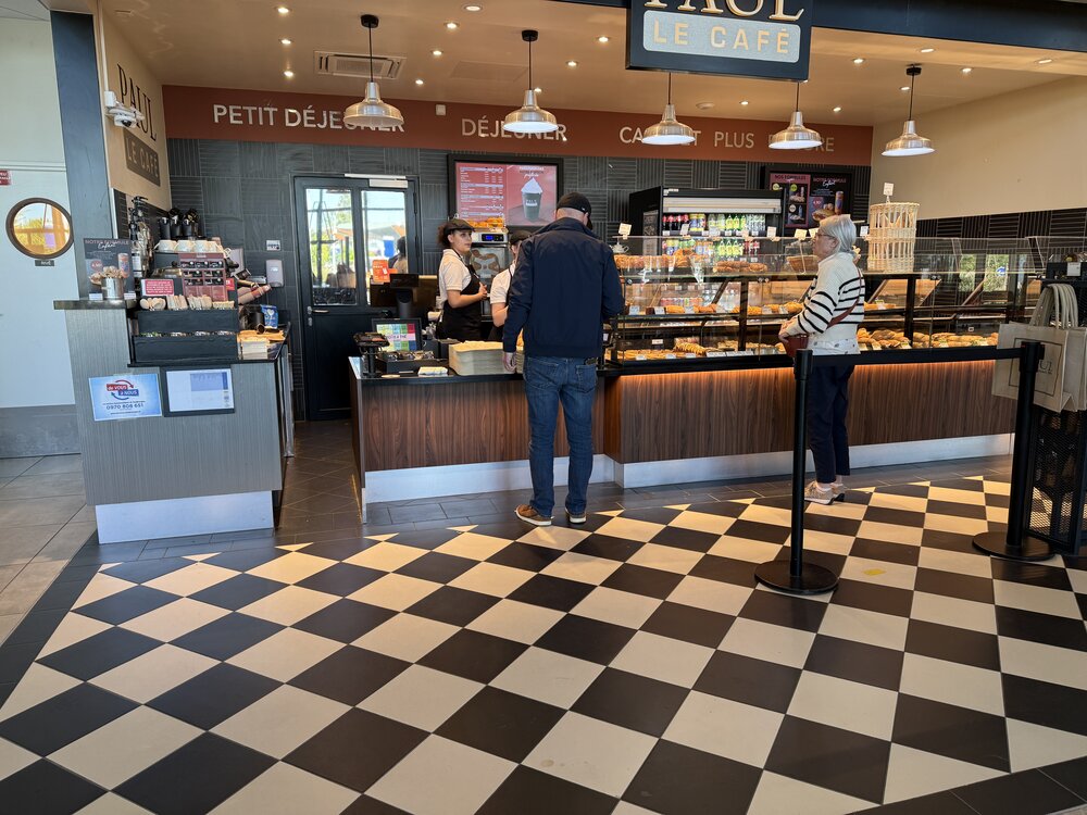 Comptoir PAUL Le Café — vitrine viennoiseries et sandwiches, clients au comptoir, sol damier