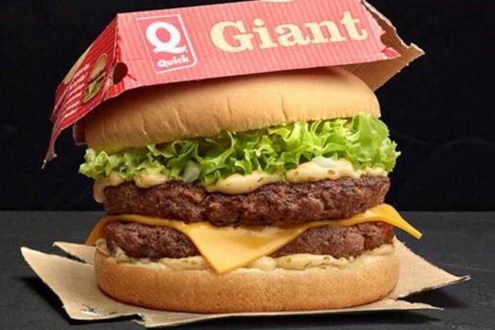 Burger « Giant » Quick en situation, sous son étui carton triangulaire rouge/jaune
