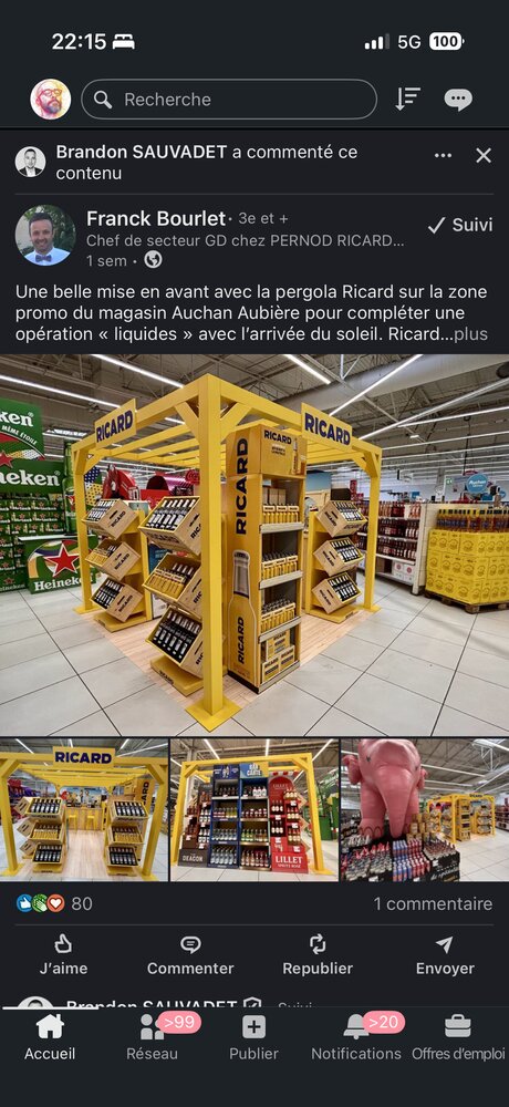 Pergola PLV jaune Ricard installée en zone promo d'un Auchan, structure ouverte avec présentoirs de bouteilles sur plusieurs niveaux