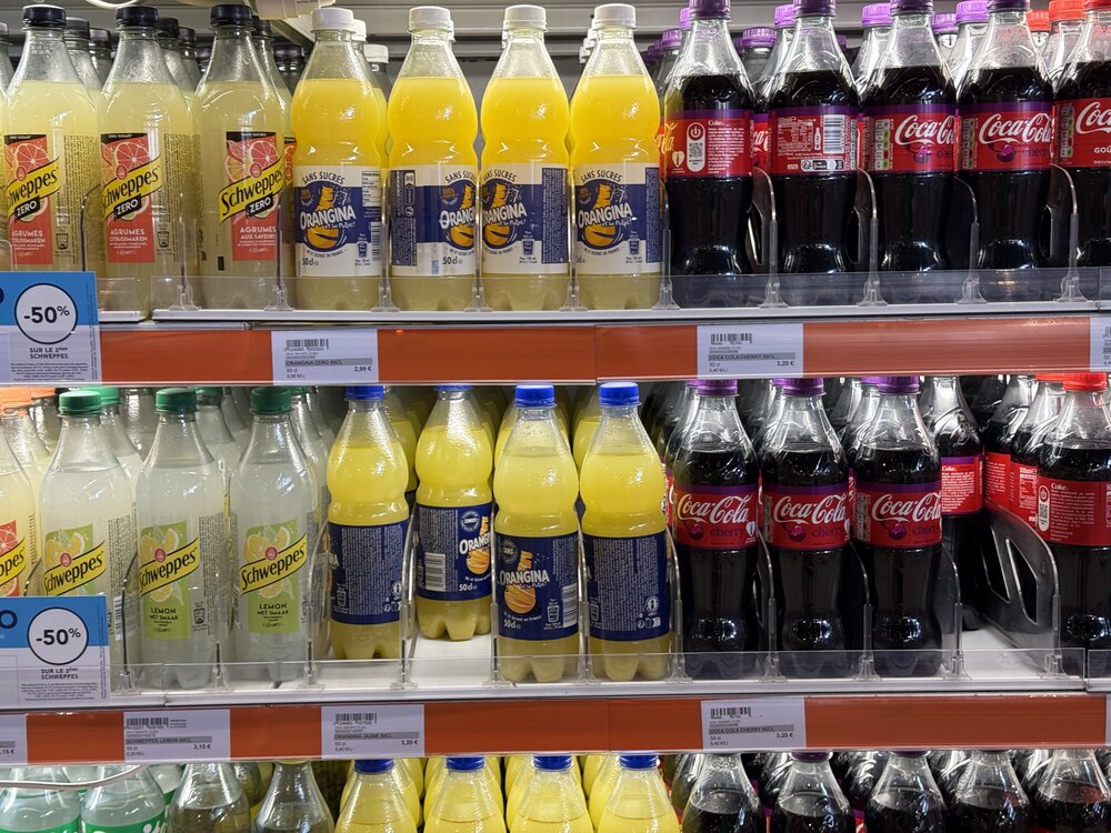 Linéaire Schweppes/Orangina/Coca-Cola bouteilles avec bandeaux promo -50%
