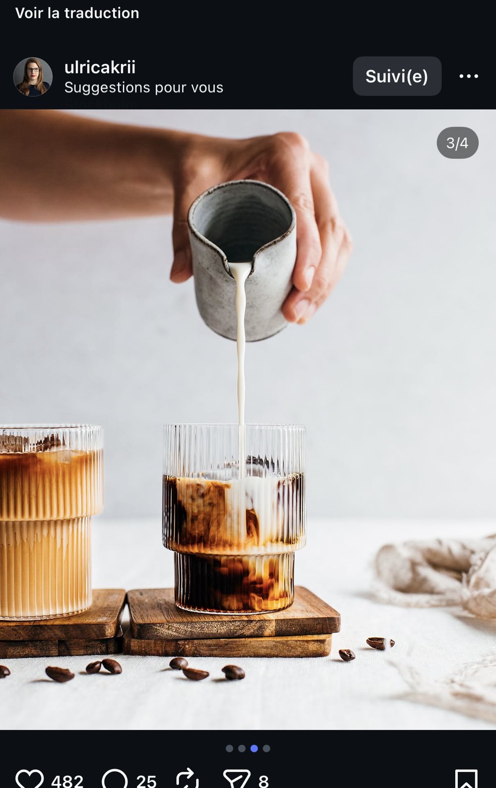 Lait versé en cascade dans un café glacé, fond clair, grains de café en premier plan